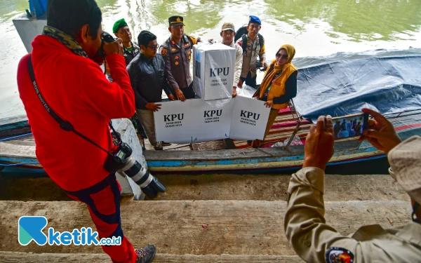 Thumbnail Seorang insan pers mengabadikan sejumlah petugas gabungan sedang menunjukkan kotak suara sebelum pemberangkatan pendistribusian logistik Pilkada serentak 2024 dari dermaga Tempat Pelelangan Ikan (TPI) Bluru Kidul menuju TPS 11 di Dusun Pucukan, Desa Gebang, Kecamatan Sidoarjo, Kabupaten Sidoarjo, Jawa Timur, Selasa 26 November 2024. Ada sekitar 121 orang yang tercatat dalam Daftar Pemilih Tetap (DPT) di TPS 11 Dusun Pucukan, dengan rincian 62 laki-laki dan 59 perempuan. (Foto: Achmad Fazeri/Ketik.co.id)